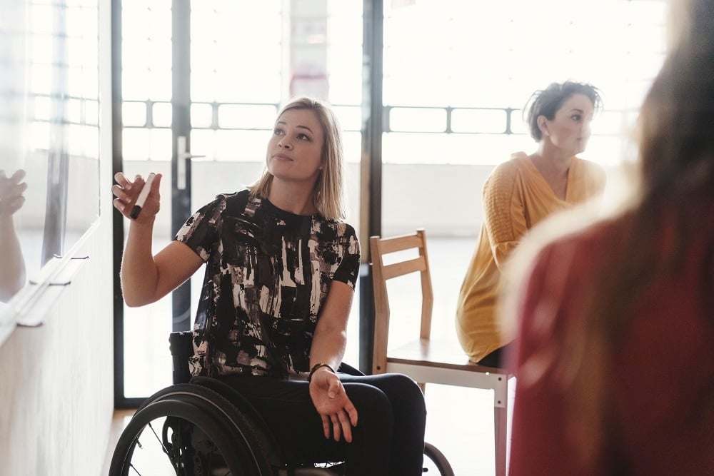 Person in wheelchair writing on a whiteboard